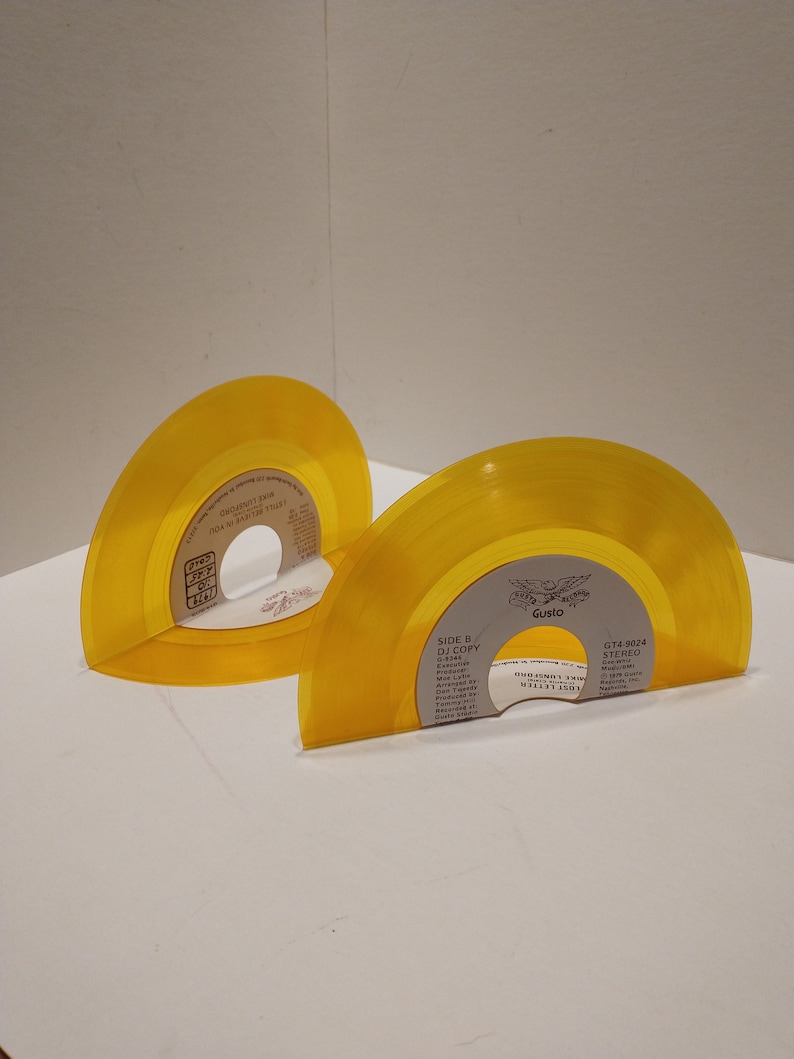 Small, shiny, round 45 size, vinyl records are bent on the bottom to make bookends. The color of the album is yellow.