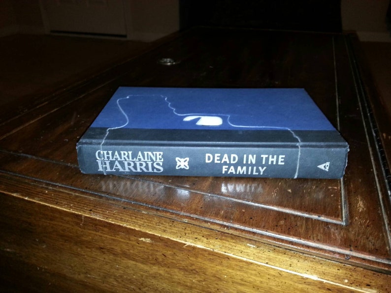 May include: A paperback book with a blue cover and white text. The title is "Dead in the Family" by Charlaine Harris.