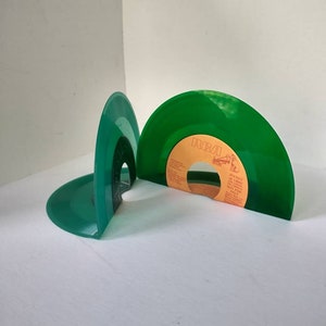 Small, shiny, round 45 size, vinyl records are bent on the bottom to make bookends. The color of the album is green.