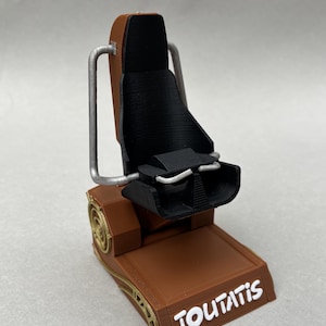 Op de afbeelding: Een bruin en zwart 3D-geprint model van een stoel met het woord "TOUTATIS" in het wit. De stoel heeft een zwarte zitting en rugleuning, met zilverkleurige steunen en goudkleurige accenten.