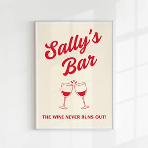May include: A white framed print with red text that says "Sally's Bar" and a graphic of two wine glasses clinking. The text below the glasses says "The wine never runs out!"