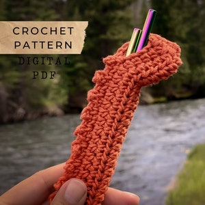 Puede incluir: Patrón de crochet para un porta pajitas reutilizable. El porta pajitas está hecho de hilo naranja y se muestra con dos pajitas de metal en su interior. El patrón está disponible para descargar en formato PDF digital.