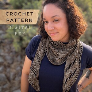 以下が含まれることがあります： 茶色とベージュのかぎ針編みのショールを身につけた女性。ショールは透かし模様のデザインです。ベージュのバナーには「CROCHET PATTERN DIGITAL PDF」と書かれています。女性は濃い青色のシャツを着ています。ショールは三角形です。
