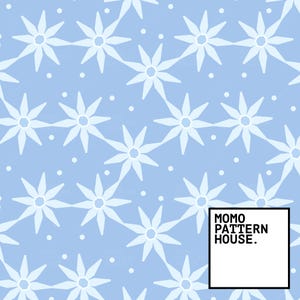 May include: A light blue pattern with white, star-shaped floral designs and small white dots. The design is repeated across the surface. The text "MOMO PATTERN HOUSE." is in a black box in the lower right corner.