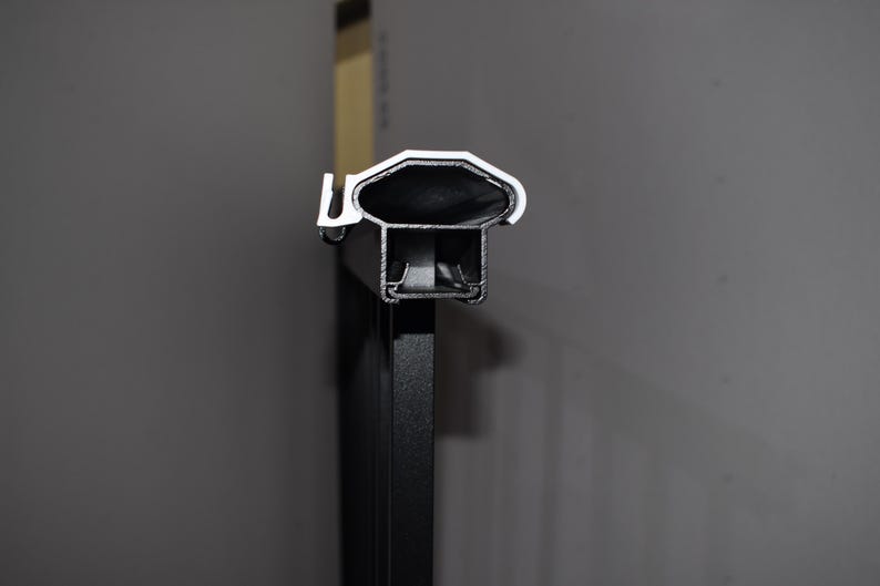 May include: Close-up of a black metal railing with a silver top. The top of the railing is designed with a series of grooves.