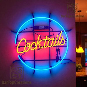 Może przedstawiać: Neonowy znak z napisem "Cocktails" w żółtym skrypcie, otoczony niebieskim neonowym okręgiem. Tło to gradient różu i czerwieni. Znak jest zamontowany na czarnej metalowej kratce.