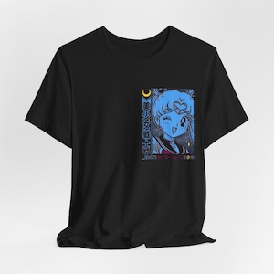 Op de afbeelding: Zwart T-shirt met een blauwe anime-stijl afbeelding van een personage met een hartvormig haaraccessoire en de tekst "美少女戦士". De afbeelding bevat een maan en sterren. Het ontwerp staat op de linkerborst van het shirt.
