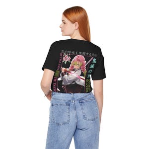 Pu&ograve; includere: T-shirt nera con grafica di un personaggio con capelli rosa e una spada, testo giapponese e le parole "MITSURI LOVE PILLAR" e "DEMON SLAYER". Il disegno &egrave; sul retro della maglietta.