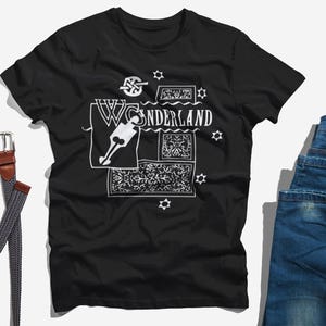 May include: Black t-shirt with a white graphic design featuring the text "WONDERLAND" and a stylized keyhole design.