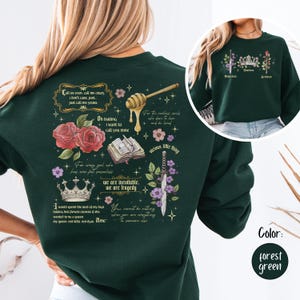 Puede incluir: Sudadera verde bosque con un diseño gráfico que presenta rosas, una corona y texto. El texto incluye frases como "Call us even, call me crazy" y "we are inevitable, we are tragedy."