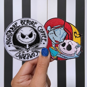 May include: Two embroidered iron-on patches featuring characters from the movie "The Nightmare Before Christmas". The first patch is a white circle with black stitching and the text "Nightmare Before Christmas". The second patch features Jack Skellington and Sally in a hug.