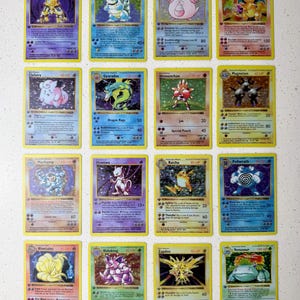 Pode incluir: Uma coleção de dezasseis cartas colecionáveis Pokemon holográficas vintage dispostas numa grelha de quatro por quatro. As cartas apresentam várias personagens, incluindo Alakazam, Blastoise, Chansey, Charizard, Clefairy, Gyarados, Hitmonchan, Magneton, Machamp, Mewtwo, Raichu, Poliwrath, Ninetales, Nidoking, Zapdos e Venusaur.