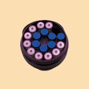 May include: A circular container filled with small vials. The vials have pink and blue caps, arranged in a pattern. The container is dark purple, and the background is a light tan color.