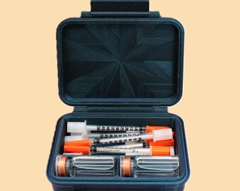 May include: A dark blue, open, small case containing several syringes with orange caps and clear vials. The case has a textured lid and a latch closure, set against a light orange background.