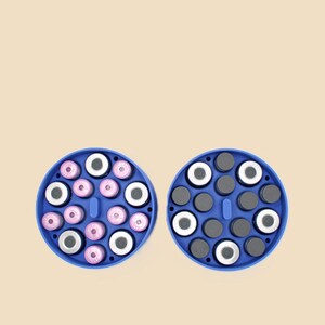 May include: Two blue circular organizers, each filled with small, round objects. One organizer contains pink and white items, while the other holds black and white items. The organizers are set against a light beige background.