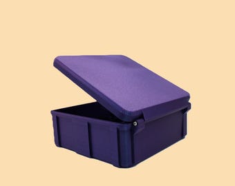 May include: A purple storage container with a hinged lid, partially open. The container is rectangular with vertical ridges on the sides. The lid is also purple and has a textured surface. The background is a light tan color.