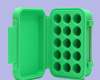 May include: Open green plastic storage box with a hinged lid. The interior has a foam insert with 15 circular indentations. The box is designed to hold small items, such as fishing lures or jewelry. The box is open, revealing the interior.