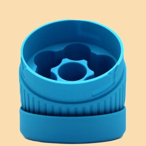 May include: A close-up of a bright blue plastic object. The object has a cylindrical shape with a ridged exterior and a star-shaped design in the center. The object is likely a bottle cap or a similar container component.