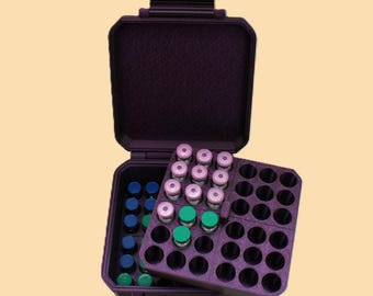 May include: A dark purple, open, hard-shell case with a handle, containing multiple small vials. The vials have various coloured caps, including pink, green, and blue. The case has a removable tray with circular cutouts to hold the vials securely.