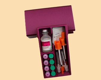May include: A magenta medical kit containing a vial, syringes, alcohol prep pads, and several small vials. The kit is open, revealing the contents, and is set against a light yellow background.