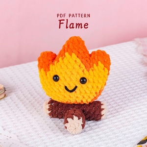 Könnte beinhalten: Ein gehäkeltes, flammenförmiges Plüschtier mit einem lächelnden Gesicht, mit orangefarbenem und gelbem Garn für die Flammen und braunem Garn für die Basis. Der Text "PDF PATTERN Flame" befindet sich darüber.