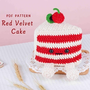 May include: A crocheted red velvet cake slice with white frosting and red stripes. The cake has a smiling face, two small feet, and a cherry on top. The text "PDF PATTERN Red Velvet Cake" is displayed.
