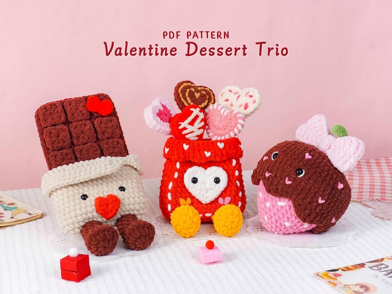 Puede incluir: Un tr&iacute;o de postres de San Valent&iacute;n de ganchillo. El conjunto incluye una barra de chocolate, un recipiente rojo con caramelos en forma de coraz&oacute;n y una fresa. El texto "PDF PATTERN Valentine Dessert Trio" est&aacute; en la parte superior.