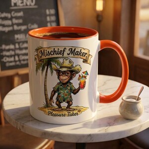 May include: A white ceramic mug with an orange interior and handle, featuring a graphic of a chimpanzee wearing a straw hat and a floral shirt, holding a tropical drink. The text "Mischief Maker" and "Pleasure Taker" is printed on the mug.