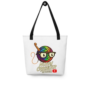 May include: White tote bag with black handles featuring a colorful yarn ball wearing glasses and holding a crochet hook. The text "NERDY CROCHETER" and "ON YOUTUBE" is printed below the yarn ball, along with a YouTube logo.