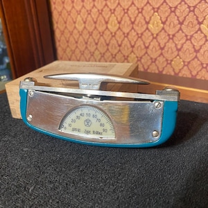 Könnte beinhalten: Ein Vintage-Messgerät in Blau und Silber mit einer gebogenen Skala, die Zahlen von 0 bis 90 anzeigt. Das Messgerät hat einen silbernen Griff und der Text "MADE IN USSR" ist sichtbar. Das Messgerät wird wahrscheinlich zur Messung von Druck oder Kraft verwendet.