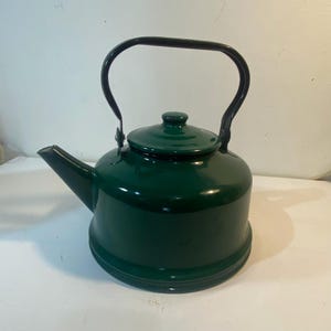 以下が含まれることがあります： 黒いハンドルと蓋が付いた、濃い緑色のエナメルケトル。 ケトルは丸みを帯びたボディ、注ぎ口、小さなノブが付いた蓋を備えています。 ハンドルはアーチ型で、ケトルの側面に付いています。
