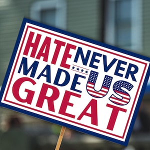 Könnte beinhalten: Ein rechteckiges Schild mit weißem Rand und blauem Hintergrund. Auf dem Schild steht "HATE NEVER MADE US GREAT" in roten und blauen Blockbuchstaben. Das "US" ist mit der amerikanischen Flagge gestaltet.