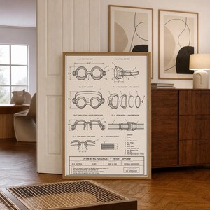May include: A framed patent print titled Swimming Goggles Patent Applied, featuring technical line drawings of goggles with various views, cross-sections, and a legend. The document includes specific imperial measurements like 6 1/2 inches and 2 1/4 inches.