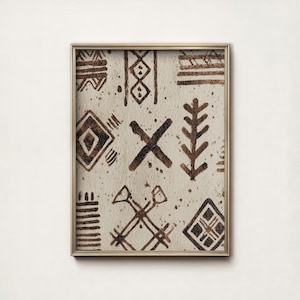 Könnte beinhalten: Ein gerahmter Druck mit beigem Hintergrund und braunen Stammesmustern. Die Muster umfassen geometrische Formen, Linien und ein „X“-Symbol. Der Rahmen ist dünn und goldfarben.