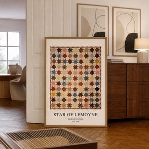 May include: A framed wall art print featuring a repeating star quilt pattern in various colours including red, blue, yellow, and brown. The text at the bottom reads STAR OF LEMOYNE, REBECCA DAVIS, USA 1846, set against a cream-coloured background.