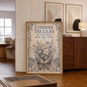 May include: A rectangular wall art print featuring a beige background with a blue floral border. The text reads: CONSIDER THE LILIES OF THE FIELD, HOW THEY GROW MATTHEW 6:28. Below the text, two hands hold a bouquet of white and blue flowers.