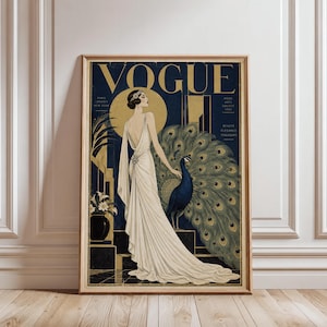 May include: A framed art print featuring a stylized illustration of a person in a long white gown standing next to a peacock. The text VOGUE is at the top in gold lettering. The background is dark blue with gold accents and geometric architectural elements.