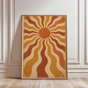 May include: A rectangular wall art print in a thin wooden frame featuring a central orange circle surrounded by radiating wavy lines in alternating shades of burnt orange, mustard yellow, and cream, with a subtle distressed texture throughout.