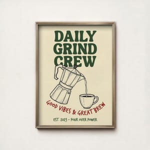 May include: A framed print with a beige background features a coffee-themed design. The text "DAILY GRIND CREW" is at the top, with an illustration of a coffee maker pouring into a cup. Below, it reads "GOOD VIBES & GREAT BREW" and "EST. 2023 - POUR OVER POWER."