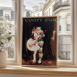 The Art Nouveau Vanity Fair print framed in ornate gold, hanging above a dark wood writing desk in a classic study.