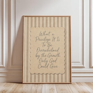 Peut inclure: Une affiche encadrée présentant un papier beige aux bords festonnés avec le texte noir : What a Privilege It Is To Be Overwhelmed by the Growth Only God Could Give, sur un fond composé de rayures verticales beiges et marron clair.