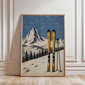 Puede incluir: Una lámina de arte mural enmarcada que muestra un paisaje de montaña estilizado con un pico nevado, un bosque oscuro de pinos y dos esquís de color amarillo brillante colocados en vertical junto a un par de bastones negros en la ladera nevada.