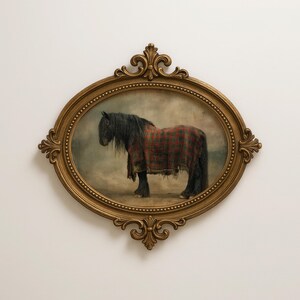 May include: An oval-shaped, gold-colored framed print of a black horse draped in a red and black plaid blanket. The horse has a long, black mane and tail. The frame has ornate detailing.