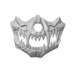May include: A light gray, sculpted half-face mask featuring a detailed animalistic design with prominent, sharp fangs and teeth. The mask includes a central circular opening for the nose and small circular holes on the sides for attachment.