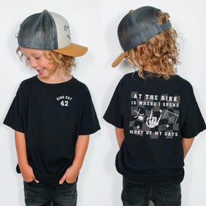 May include: Black t-shirt with "RINK RAT 42" printed on the front and "AT THE RINK IS WHERE I SPEND MOST OF MY DAYS" on the back. The shirt is paired with a trucker hat with a tan brim and a gray mesh back.