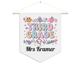 Pode incluir: Bandeira de bandeirola branca com as palavras "THIRD GRADE" em letras coloridas em estilo retrô. A bandeira inclui ilustrações de um rosto sorridente, uma maçã, um livro, um lápis e um globo. O nome "Mrs Kramer" está impresso abaixo.