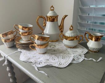 Juego de té KPM blanco con detalles dorados, 6 tazas, platillos, tetera, lechera y azucarero.