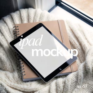 May include: A black tablet with a blank screen, labeled "ipad mockup", rests atop a tan notebook and a cream-colored knitted blanket. The notebook has a spiral binding and an elastic band closure. The number "no. 63" is in the bottom right corner.