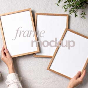 Può includere: Tre cornici in legno con inserti bianchi sono disposte su una superficie di colore chiaro. Le cornici sono tenute in mano e il testo "frame mockup" è sovrapposto alle cornici. Le cornici hanno una finitura in legno naturale.