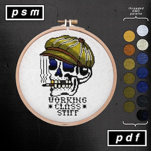May include: Cross-stitch embroidery in a wooden hoop. The design features a skull wearing a green cap and smoking a cigarette. Text reads "WORKING CLASS STIFF". A color palette is shown on the right, and the letters "psm" and "pdf" are in the corners.